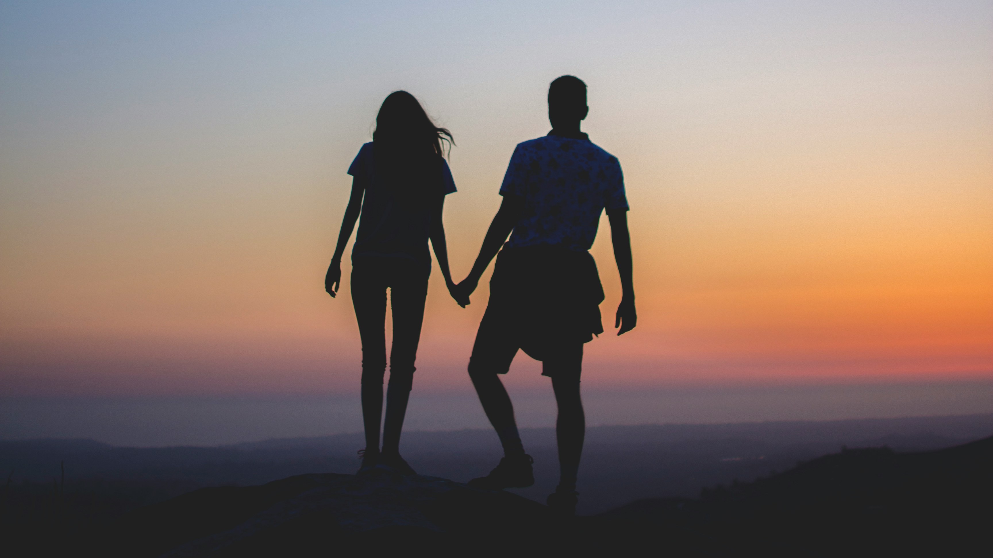 Silhouetted couple holding hands at sunset